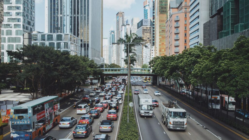 vehicles traveling on road between buildings during daytime